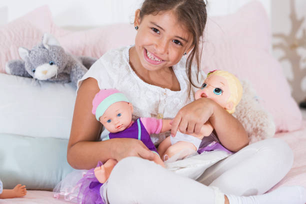 istock Little girl holding dolls sitting on bed 926396722