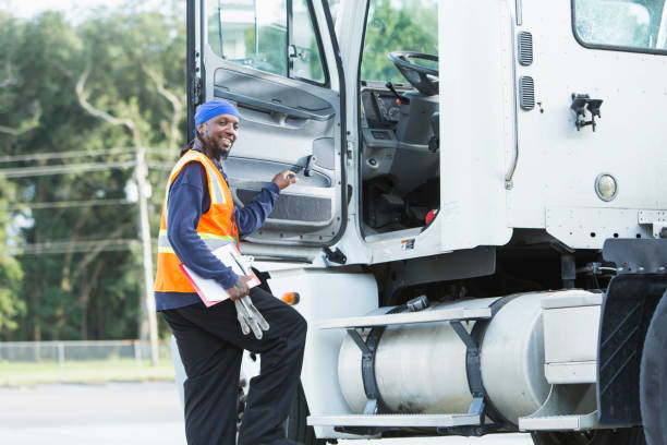 Semi-truck driver climbing into cab A semi-truck driver climbing into the truck cab, smiling at the camera. The mature black man in his 40s is wearing a reflective vest. do rag stock pictures, royalty-free photos & images