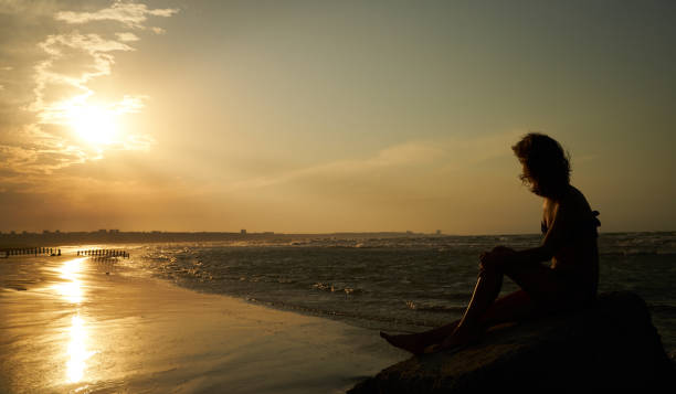 istock Woman enjoying beautiful sunset on the beach 926401084