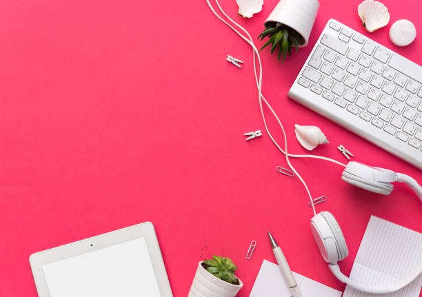 istock Creative Flat lay accessories on pink background. Top view office equipment concept with headphones, keyboard and tablet 926403234