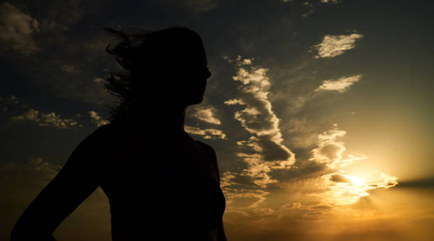 istock Woman with open arms standing at sunset seaside beach 926403252