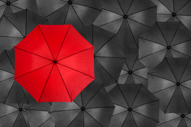 rendering 3d di ombrello rosso vivo aperto che sovrascriva una quantità infinita di ombrelli neri simili - standing out from the crowd individuality umbrella contrasts foto e immagini stock