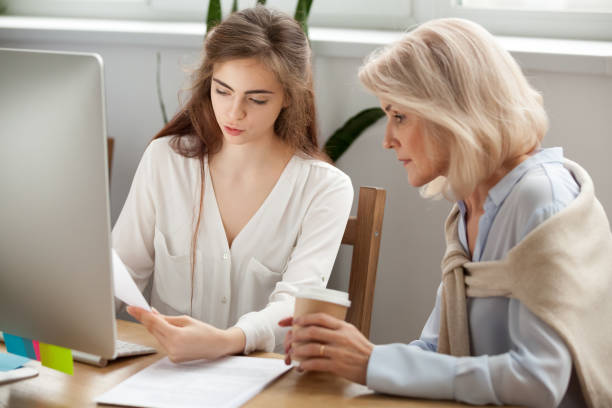 istock Young and older businesswomen discussing documents working together in office 926404240