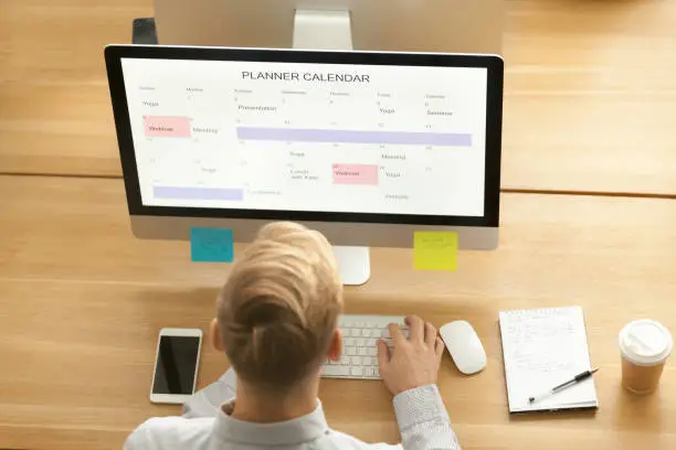 Photo of Businessman using planner application on computer in office, top view