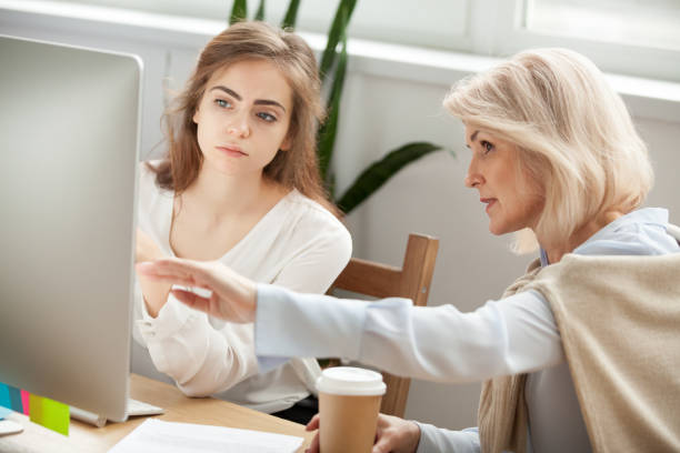 Senior and young colleagues discussing online project looking at screen Senior and young female colleagues discuss online project look at pc screen, older mentor teaches young woman explains corporate software work, aged executive helps intern, teamwork on computer task guidance support stock pictures, royalty-free photos & images