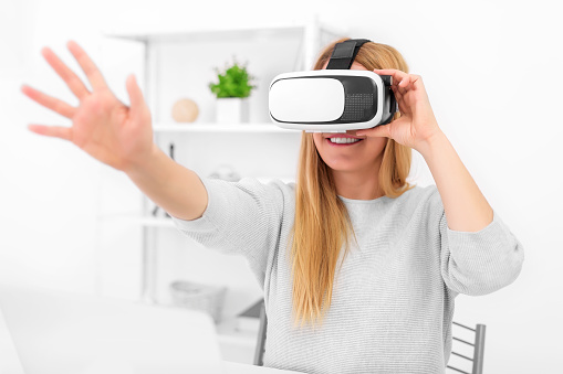 Virtual reality goggles. An attractive young woman uses virtual reality glasses in a bright room. Focus on the glasses.