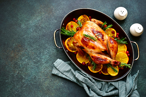 Roasted chicken with oranges ,rosemary and cranberries in a skillet pan.Top view with copy space.