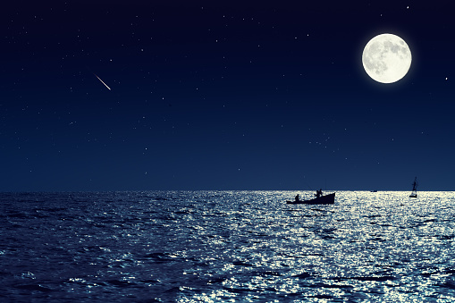 the full moon above the ocean.