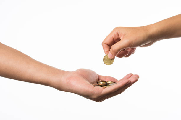 woman hand giving golden coin to another hand. stock photo