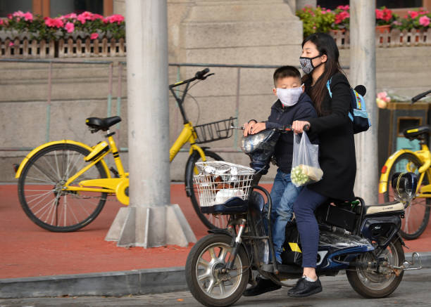 mujer y niño bicicleta motorizada en shanghai - candid downtown district editorial horizontal fotografías e imágenes de stock