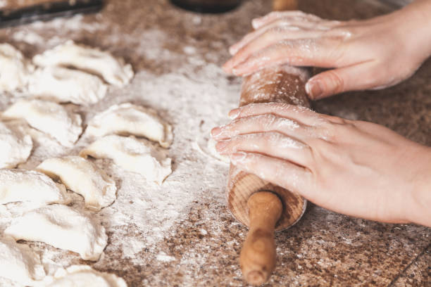 istock Female hands roll out dough with wooden rolling pin 926470894