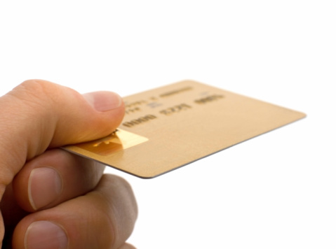 Closeup of a hand holding a credit card with selective focus in the foreground. Photographed over a white background.