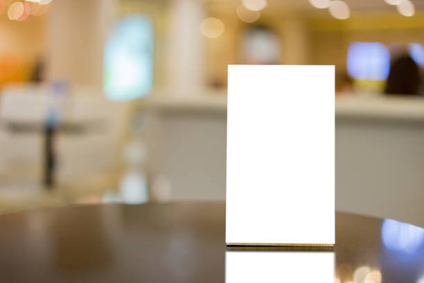 istock Mock up Menu frame on Table in Bar restaurant ,Stand for booklets with white sheets of paper acrylic tent card on cafeteria blurred background 926501818
