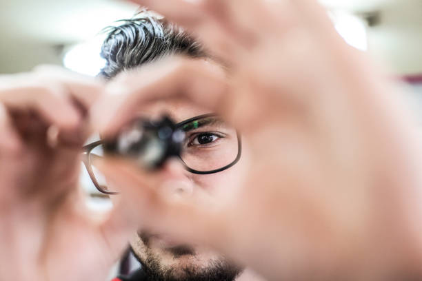 Worker looking at a microchip Worker looking at a microchip. About 25 years old Caucasian male with beard and glasses. nanotechnology stock pictures, royalty-free photos & images