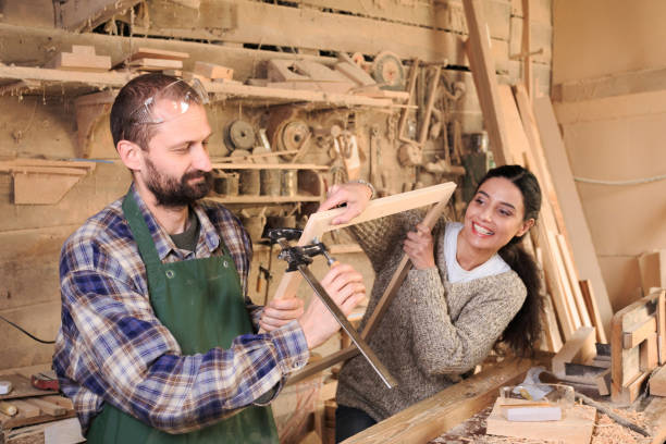 Couple carpenter workers making a frame in their workshop stock photo