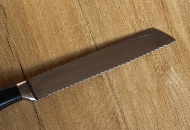 木製の背景にあるキッチンでパン切りナイフ - knife edge ストックフォトと画像