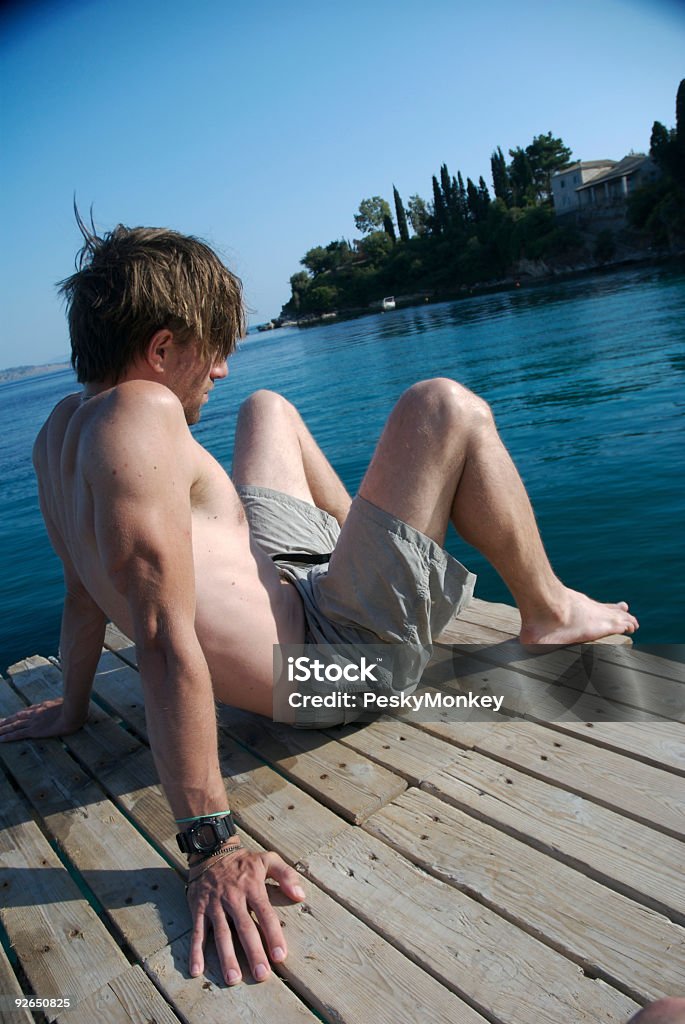 Człowiek siedzi na słoneczny Dock - Zbiór zdjęć royalty-free (Bez koszulki)