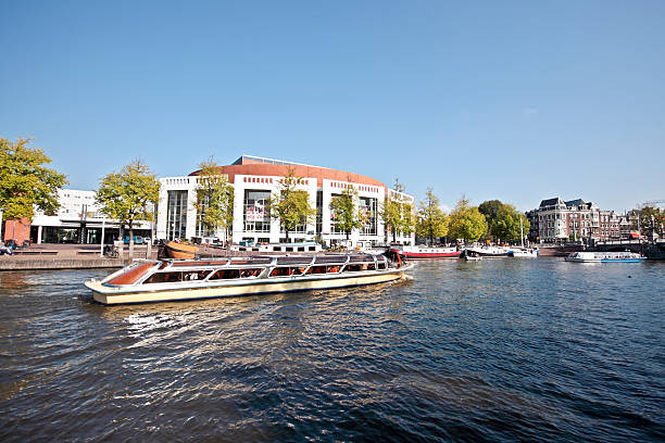 Cruising on river Amstel with the Stopera in Amsterdam Netherlands  stopera stock pictures, royalty-free photos & images
