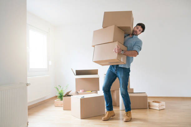 Nothing's Too Tough For This Guy Funny young man clumsy carrying a stack of cardboard boxes while moving into a new apartment. big cardboard box stock pictures, royalty-free photos & images