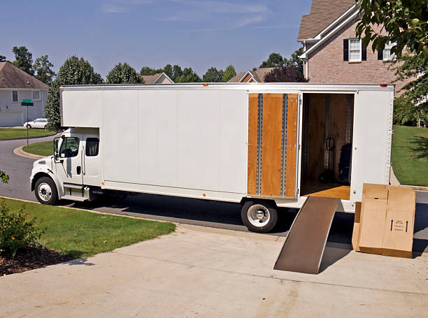 Moving and storage truck Side View With Open Door white moving and storage truck with an open door for loading household items. Image shot in a residential neighborhood on a sunny day. The open door has an extended ramp for loading. Utilize the blank side of the truck for your copy.  moving van stock pictures, royalty-free photos & images