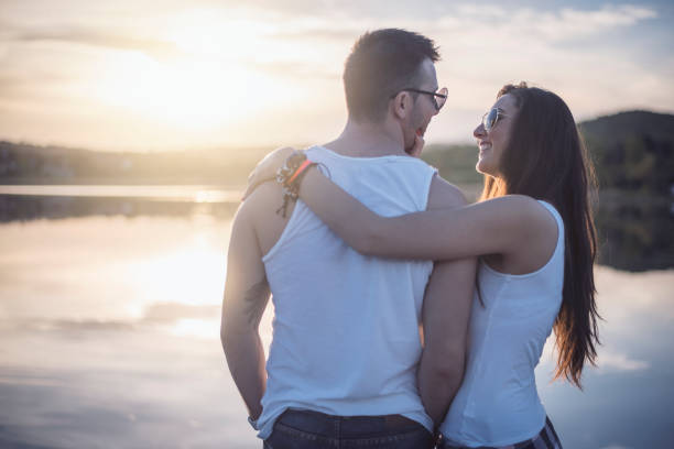 Love couple in nature enjoys on great sunset at the dock by the lake.
