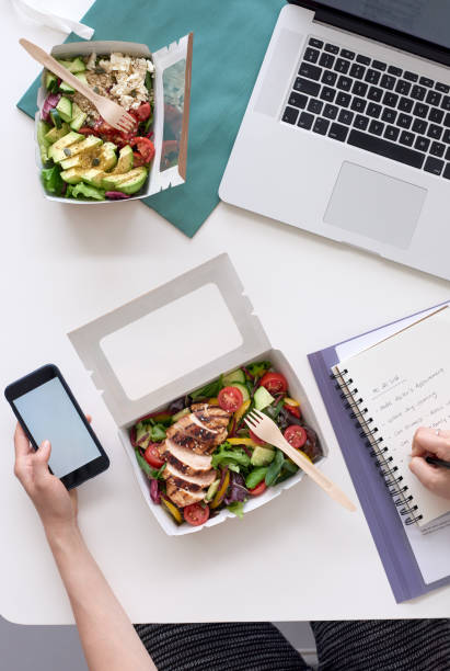 istock Overhead view of hands holding cellphone with takeout lunch 926527116