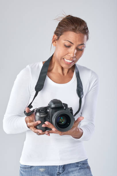 istock Middle aged woman holding DSLR camera with uncertainty 926529920