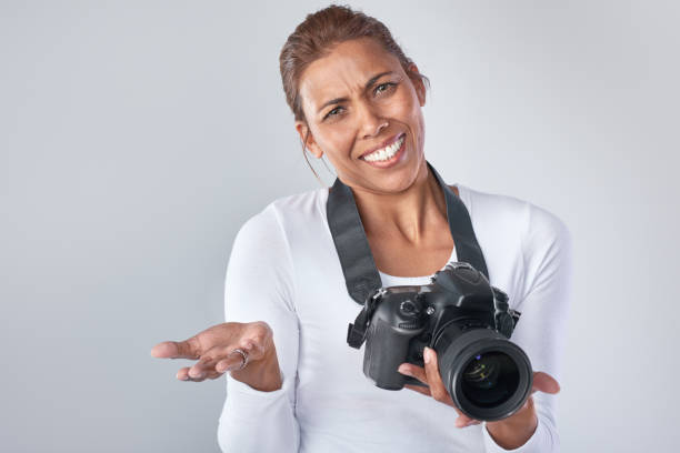 istock Middle aged woman shrugging shoulders while holding DSLR camera 926529950
