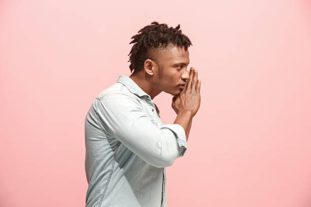 istock The young man whispering a secret behind her hand over pink background 926542568