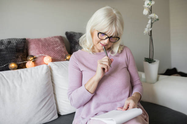 istock Senior lady in glasses holding notepad and ball pen thinking 926546244
