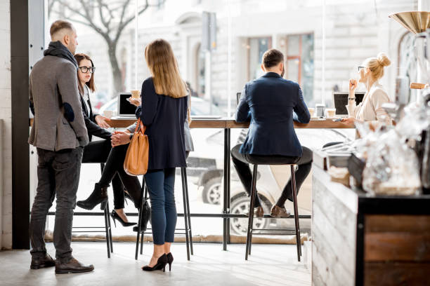 Business people having a conversation and working with laptops during the coffee break in the cafe