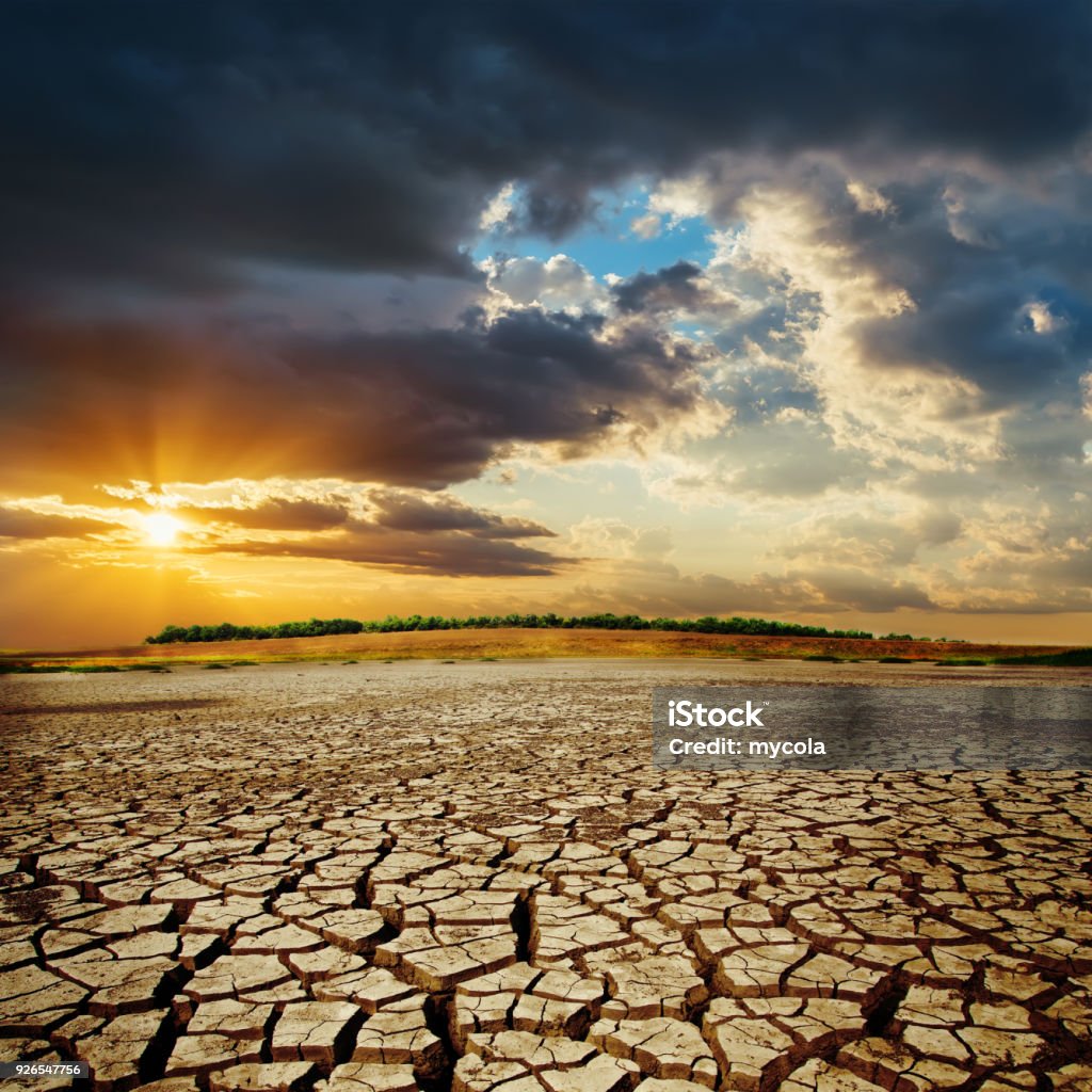 tierra de sequía en la puesta de sol. espectacular cielo sobre el desierto. cambio climático - Foto de stock de Sequía libre de derechos