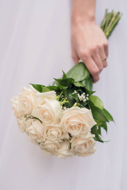 Detail of a bride with a bouquet of white roses stock photo