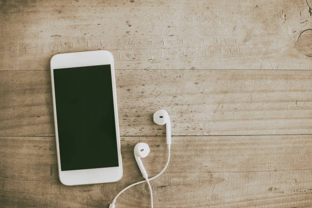 istock White mobile phone and earphone on wooden background 926551242