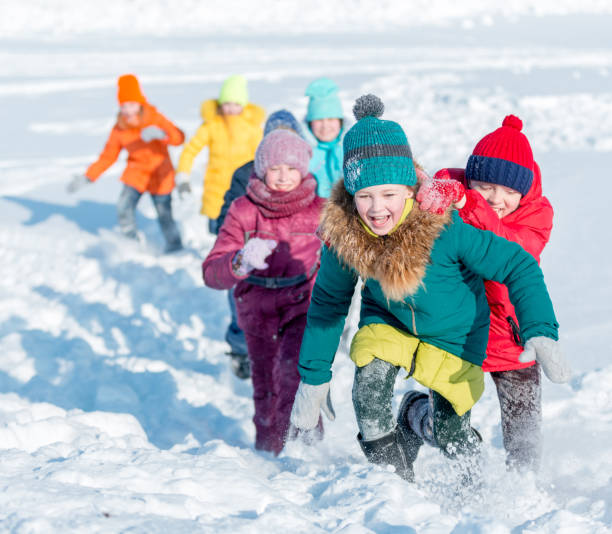 雪の上の陽気を実行している子供たち ストックフォト