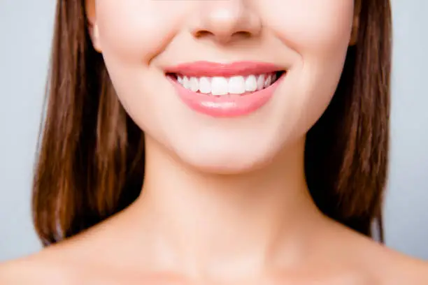 Photo of Concept of healthy wide beautiful smile. Cropped close up photo of healthy without caries shiny toothy woman's smile, isolated on grey background