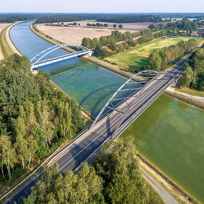Aerial photograph of infrastructural facilities for cars, trains and ships, overflight of a canal with a railway bridge and a road bridge, made with drone