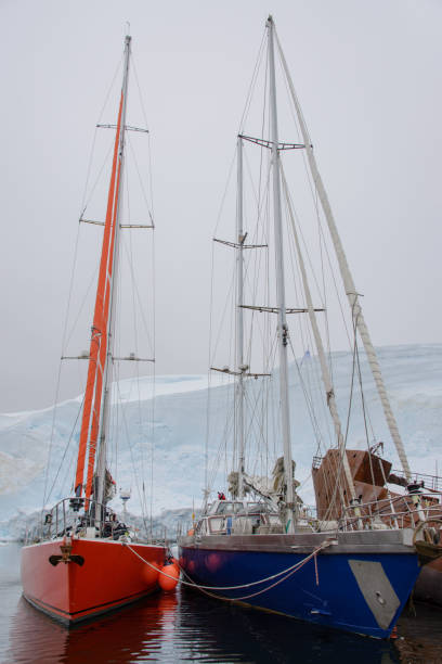 istock Two sailing yachts in the antarctic sea moored to rusty wreck 926558620