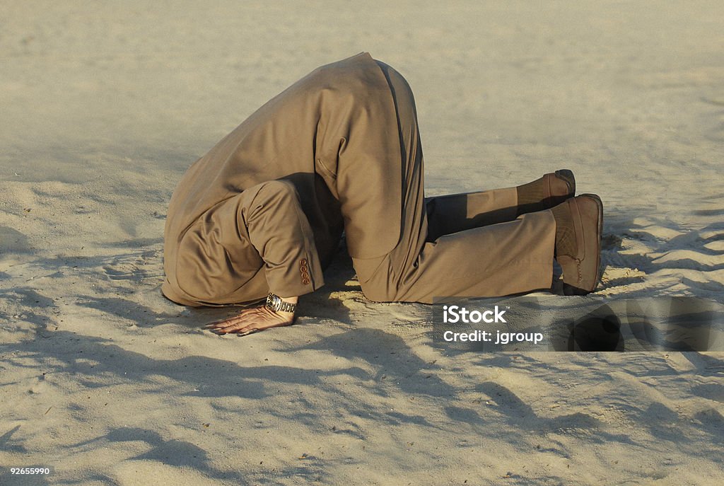 Businessman with head stuck in sand at the beach  Ignorance Stock Photo