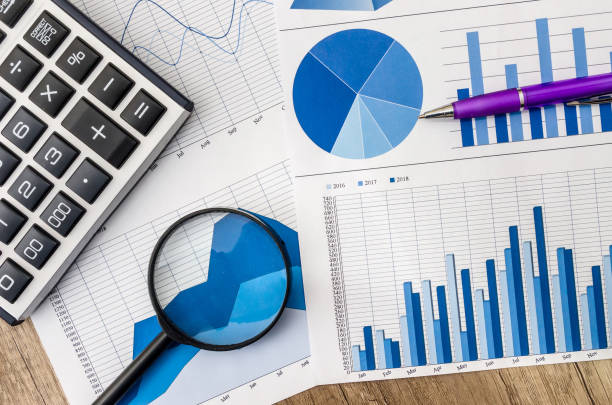 istock Business graph with magnifying glass and calculator pen on table 926563182