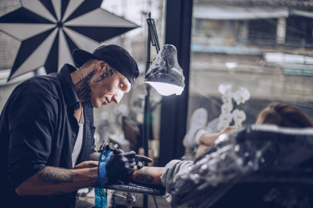 donna che si tatua il braccio - tatuare foto e immagini stock