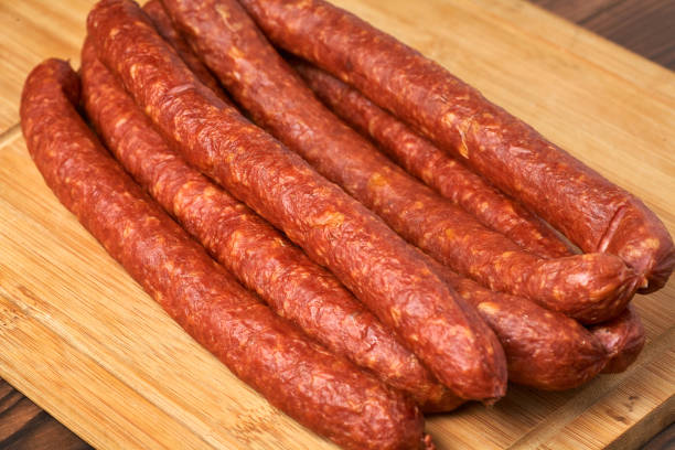 istock Thin smoked sausage on a wooden background. Close-up. 926566416