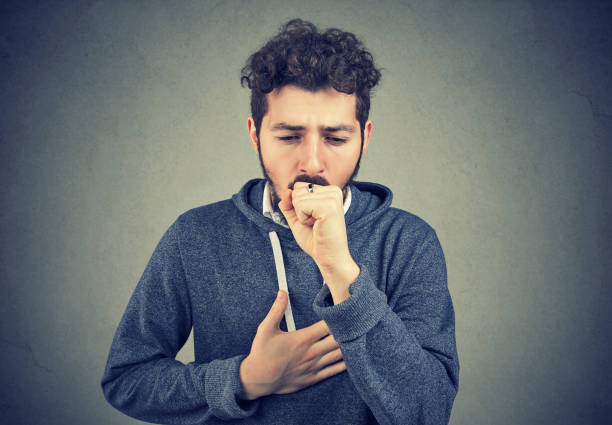 Sick man coughing with pain Young man having asthma problems and coughing badly covering mouth and holding hand on chest. bronchitis stock pictures, royalty-free photos & images