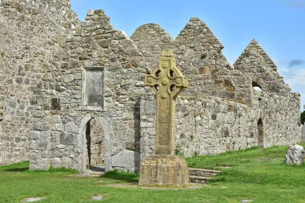 Ruins of medieval stone Christian church called Temple Dowling with Celtic sandstone high cross in Clonmacnoise in Ireland.