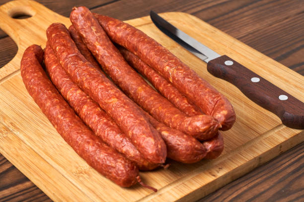 istock Thin smoked sausage on a wooden background. Close-up. 926571042