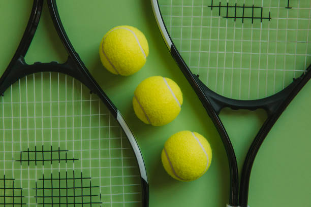 istock Three tennis balls and two rackets on green background. 926574124