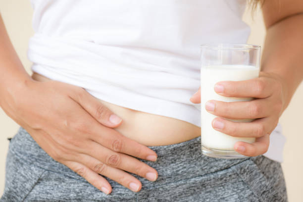 Woman hand holding glass of milk having bad stomach ache because of Lactose intolerance. Woman hand holding glass of milk having bad stomach ache because of Lactose intolerance. health problem with dairy food products, Healthcare and medical concept. lactose fermentation stock pictures, royalty-free photos & images