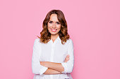 Concept of femininity womanhood tenderness. Portrait of happy smiling confident mature joyful woman with perfect make up, wearing white shirt, standing with crossed hands, isolated on pink background