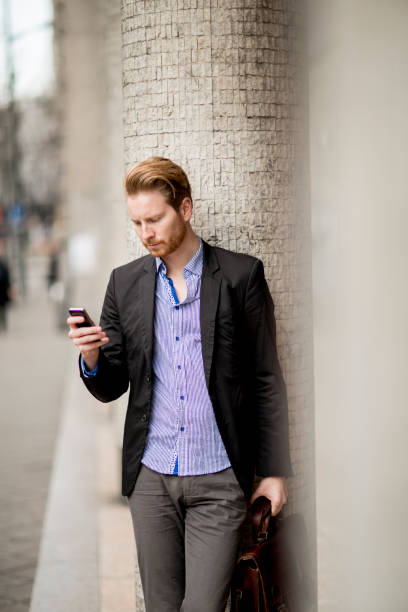 istock Ginger businessman waiting for transportation and using mobile phone 926591066