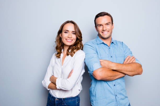 he vs she happy together. close up portrait of attractive, caucasian, lovely, cute, adult couple in casual outfit  looking at camera standing with crossed arms over grey background - contemporary friendship businessman business imagens e fotografias de stock